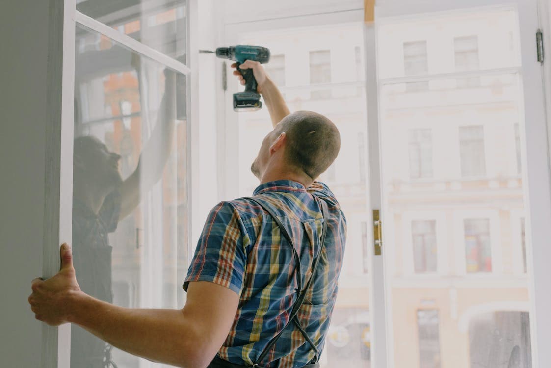 Handyman using a drill to repair a window frame