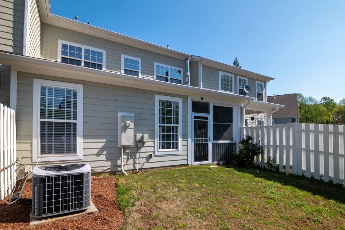 Residential AC condenser unit next to a suburban home